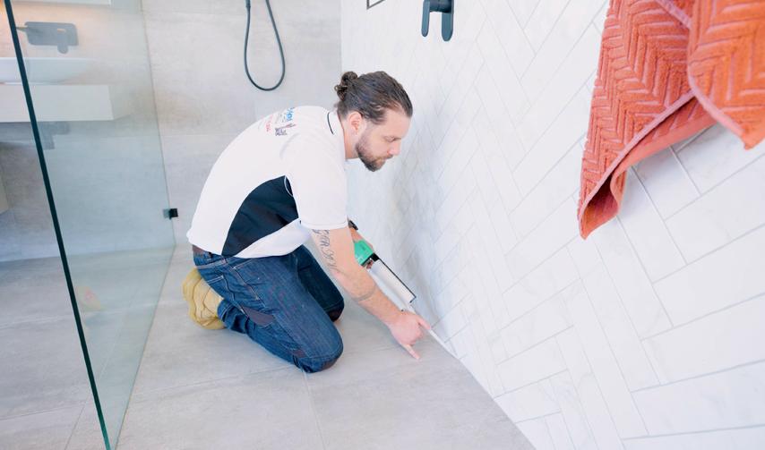 Frameless glass shower screen with rainfall showerhead and tiled bathroom interior
